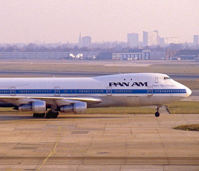A Pan Am Boeing 747 "Clipper Maid of the Seas" on an airport tarmac with a city skyline in the background